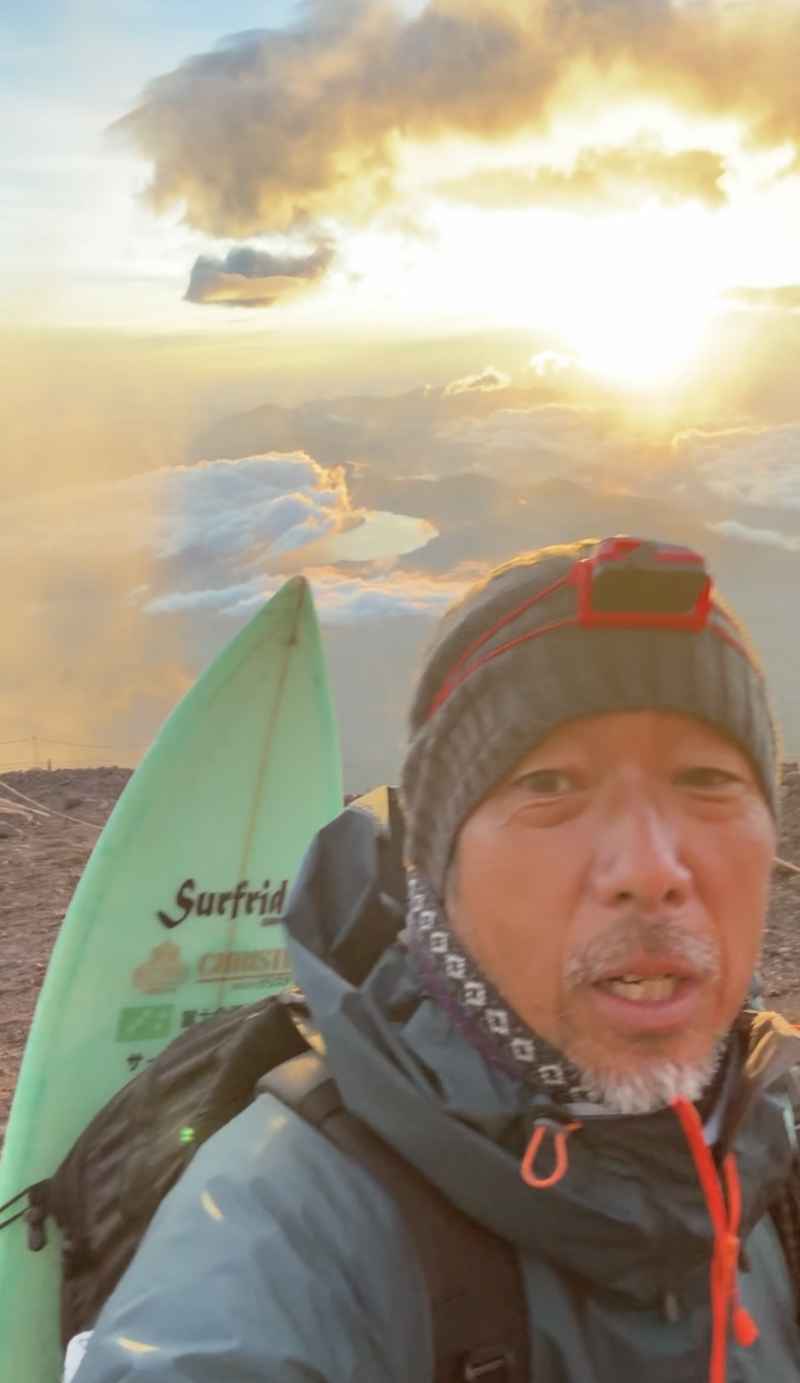 富士山頂でサーフボードを持つ義忠さん
